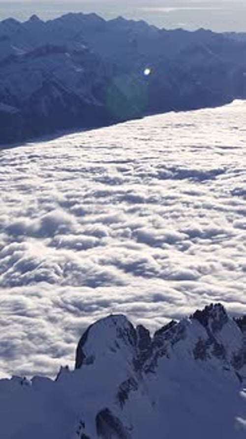 Le majestueux sommet de la montagne s'élève au-dessus de la douce couverture de nuages dans le ciel lumineux