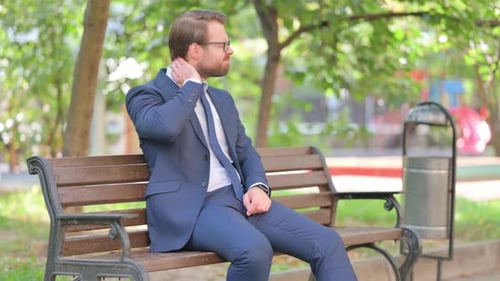 Man on Park Bench Massaging Sore Neck