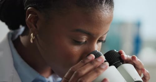 Female Scientist Using Microscope in Bright Laboratory