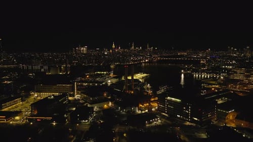Fly Above City Illuminated Buildings on Waterfront and High Rise Office Buildings in Distance
