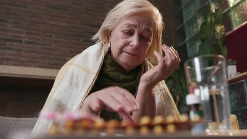 Close Up Elderly Woman with a Headache Measures the Temperature Take Pills Sitting Fever in Home