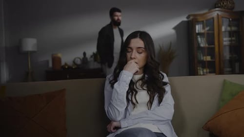 Sad Woman on Sofa During Argument with Man