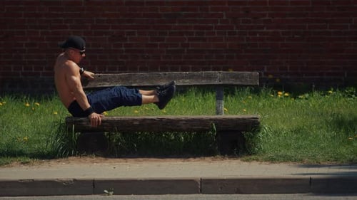 Shirtless Bodybuilder on Bench Doing Leg Raises and Handstand Pushups Effective and Complex Exercise