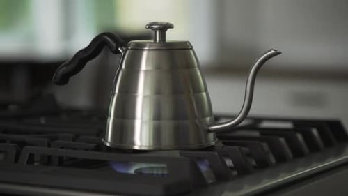 Silver Kettle Steaming on Gas Stovetop in Kitchen