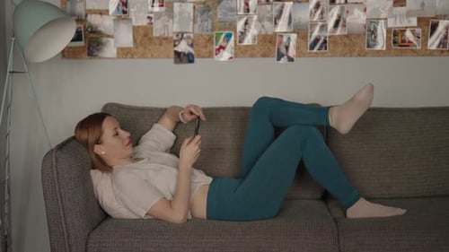 Woman Relaxing on a Sofa Using a Smartphone at Home