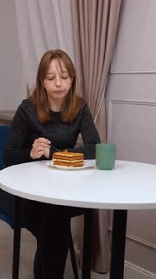 Woman Eats Cake at Table Indoors