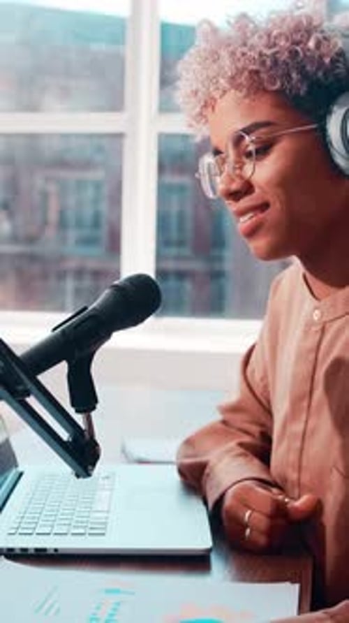 Une jeune femme afro-américaine sourit vivement tout en parlant dans un microphone professionnel