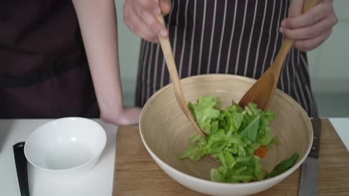 People Mixing Salad in a Bowl with Spoons