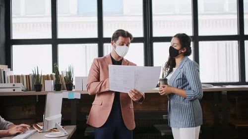 Young architects wearing face masks work in modern office during coronavirus pandemic