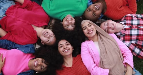 Multiracial female friends laughing together in a summer meadow in London