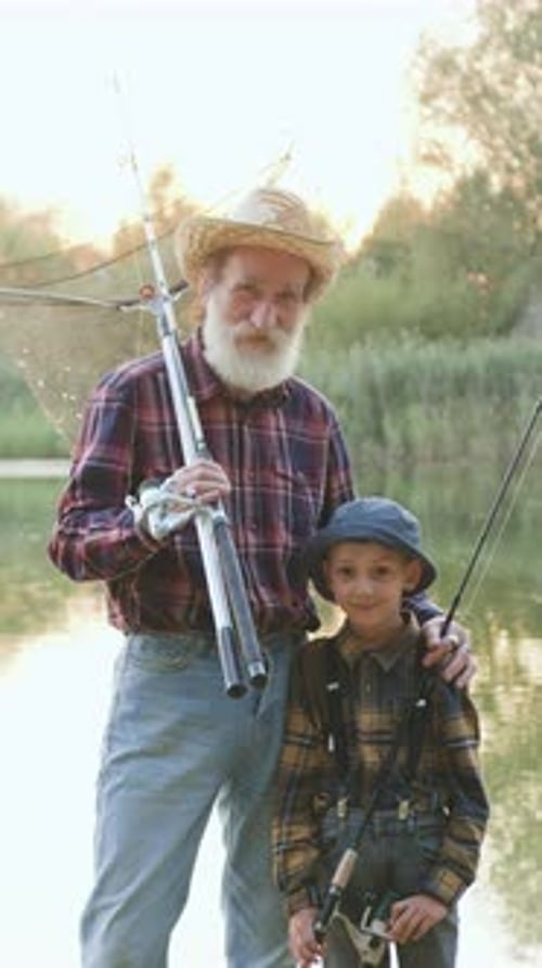Close Up of Attractive Carefree Satisfied Mature Fishman and His Small Grandchild Anglerbeginner