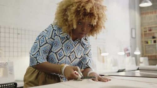 Seamstress Cutting Fabric with Scissors in Sewing Workshop