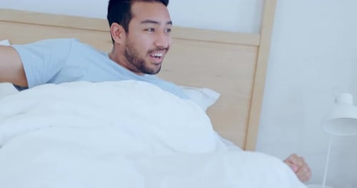 Man Wakes Up and Stretches in Bed