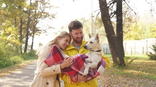 Couple Walking Dog Wrapped in Blanket in Autumn Park