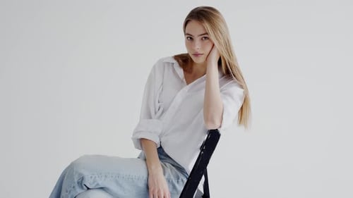 Woman Posing Elegantly on Chair in White Studio