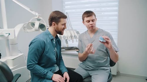 Dentist Explains Procedure with Model to Patient