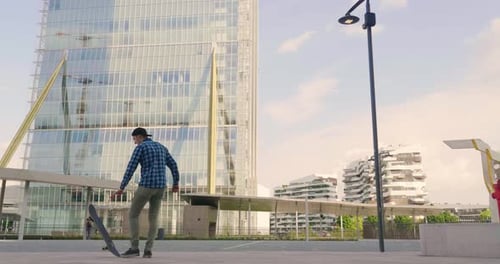 Portrait a boy practices skateboarding in the middle of the city, between buildings and skyscraper