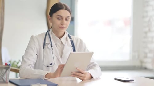 Young Female Doctor using Tablet in Clinic