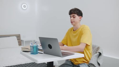 A Tired Teenager Removes His Headphones Closes His Laptop and Falls Asleep on the Desk with His Head