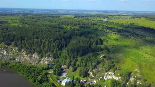 Top view of village on river bank on background of horizon with forest