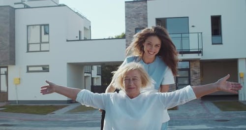 Young Woman Pushing Senior Woman in Wheelchair Outdoors