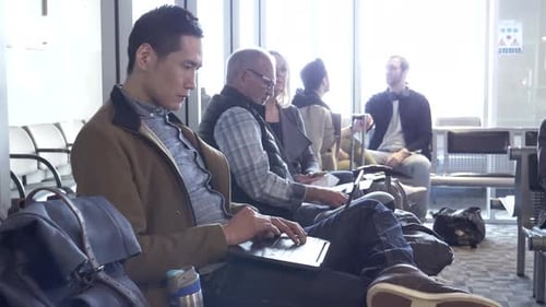 Un homme asiatique mature utilise un ordinateur portable en attendant dans la salle des départs de l'aéroport