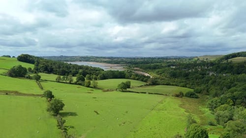 Expansive aerial view of rolling green hills, forest, and distant lake