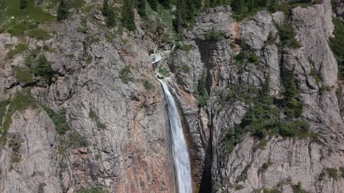Waterfall Cascades Down Rocky Mountainside in Tranquil Forest Setting