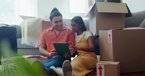 Couple Using Tablet Amongst Moving Boxes in New Home