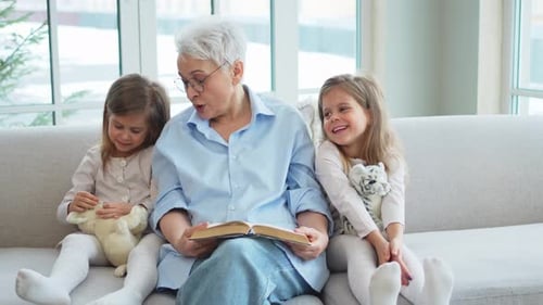 Grandmother Reading Story to Granddaughters on Couch