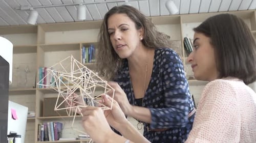 Two Women Discussing Geometric Model In Creative Studio