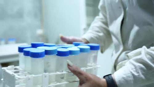 A female lab technician carries test tubes for analysis. Science research center.