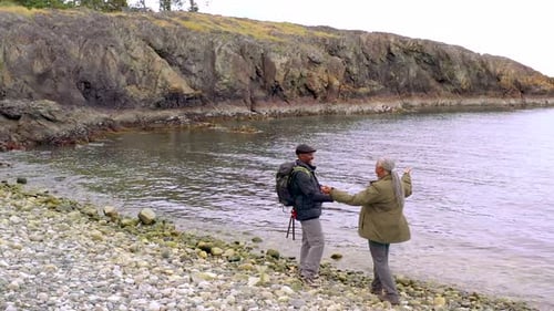 Couple Embracing on Rocky Beach Near Ocean
