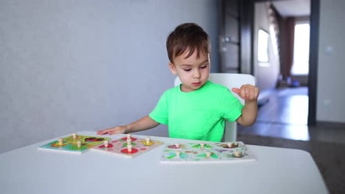 Adorable dark-haired toddler playing with three sets of puzzles. Little kid learning through a game.