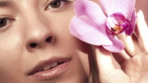 The Face of a Young Woman with Clean Skin in the Studio on a Pink Background Close Up A Woman