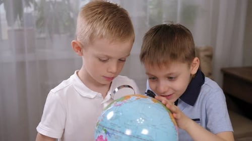 Two Young Boys Explore Globe with Magnifying Glass