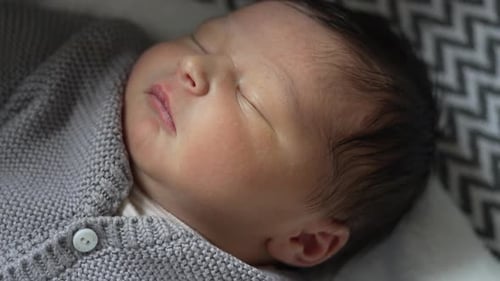 Close-up of a peacefully sleeping newborn baby wrapped in a cozy blanket, highlighting the