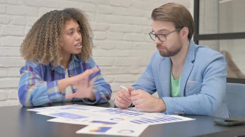Woman Explains Charts to Man in Office Setting