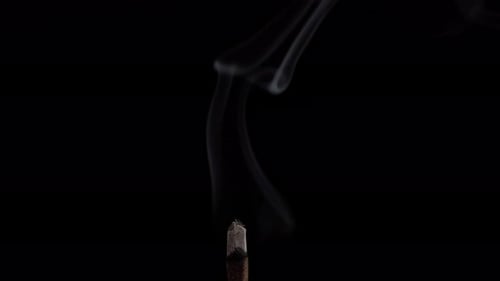 Puffs of smoke from a smoldering incense stick for meditation and relaxation.