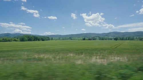 Idyllische toskanische Landschaft mit üppigen grünen Feldern und blauem Himmel. Blick auf das Zugfenster.