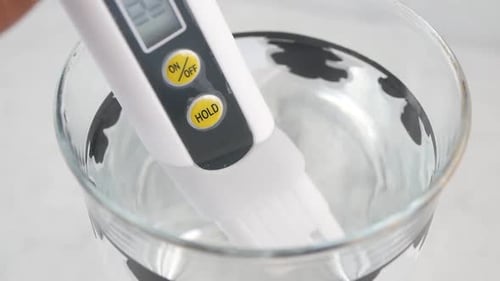 Mesurer la qualité de l'eau à l'aide d'un testeur numérique dans un verre