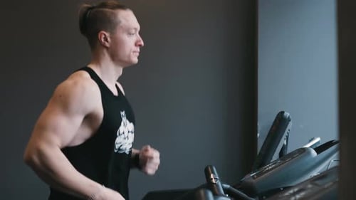 Muscular Male Athlete Exercising on Treadmills in the Modern Gym Doing Fitness Exercise