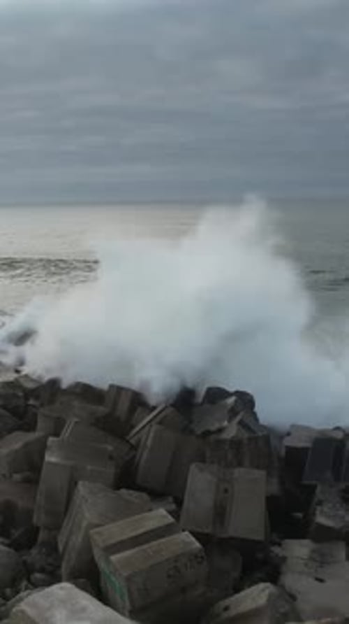 Vertikales Video von großen Wellen, die am Sturmtag auf den Pier stürzen
