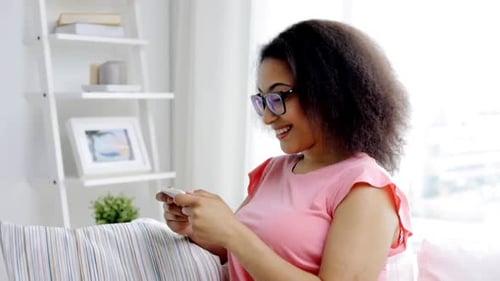 Smiling woman using phone on sofa indoors