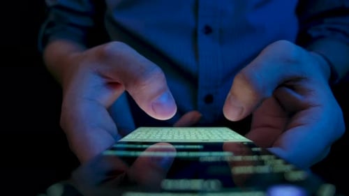 Man Typing on Smartphone Keyboard at Night