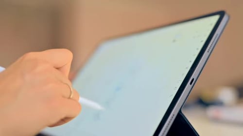 Woman drawing on a tablet with white pencil, close up