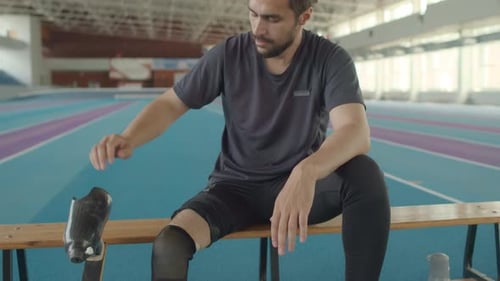 Man Adjusting Prosthetic Leg in Gymnasium