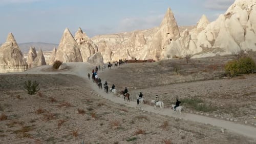 Turkish Men And Caravan Of Horses Passing Across The Cappadocia Landscapes, Turkey. - Wide Shot