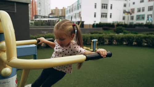 Young Girl Enjoys Outdoor Exercise Equipment at a City Park in the Afternoon