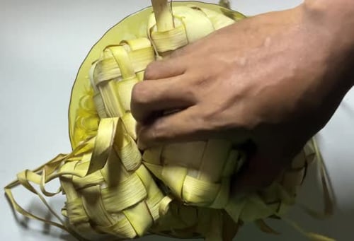 Hand Opening Ketupat Rice Cakes in Bowl